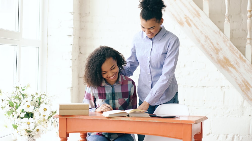 Tutor helping a smiling student with homework at a desk